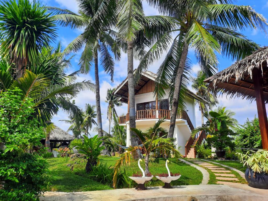 a house with palm trees and statues in front of it at Palmera Palma Top Floor in Moalboal