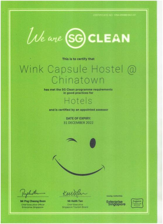 a green sign with a smiley face on it at Wink at Mosque Street in Singapore