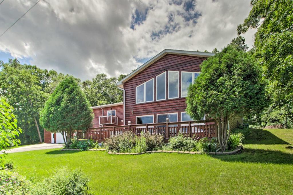 a wooden house with a deck on a lawn at Spacious Frazee Home with Direct Lake Access! in Frazee