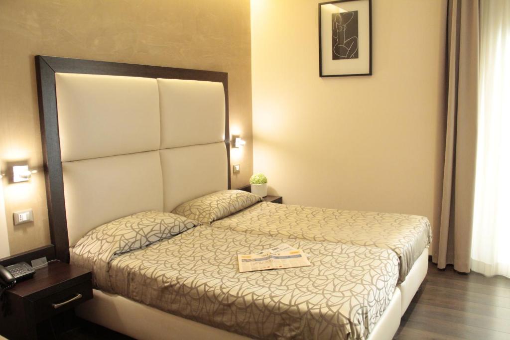 a hotel room with a bed with a book on it at Catone District Hotel in Rome