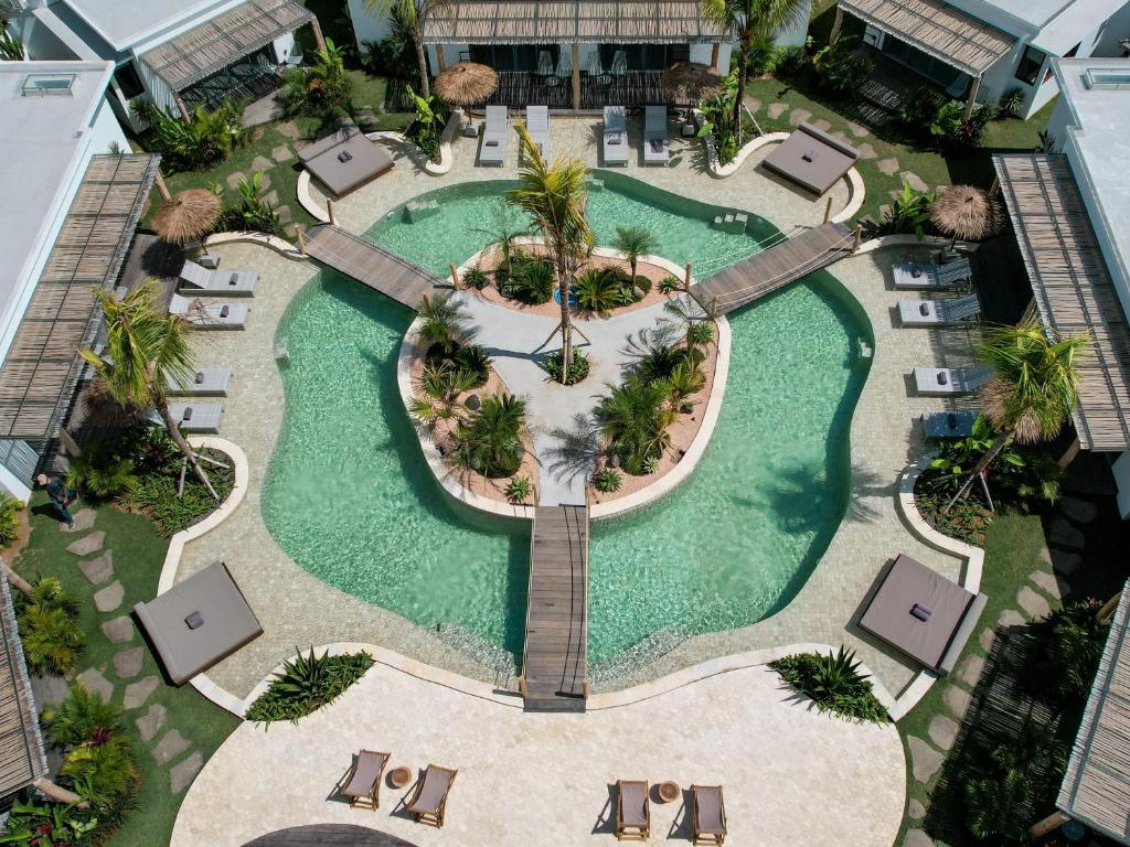 an overhead view of a resort pool with chairs and palm trees at Kalia Bingin - Adult only in Uluwatu