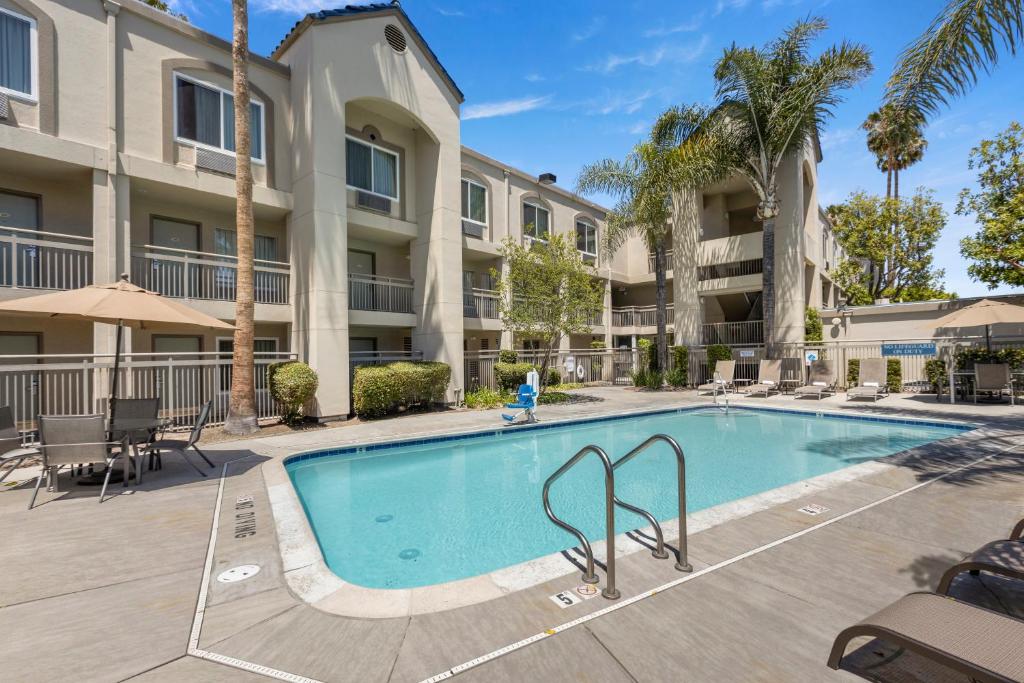 a swimming pool in front of a building with palm trees at Good Nite Inn Buena Park in Buena Park