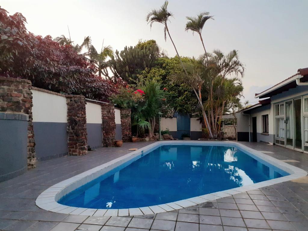 een blauw zwembad in een tuin met palmbomen bij Blue Lantern Ramsgate in Margate