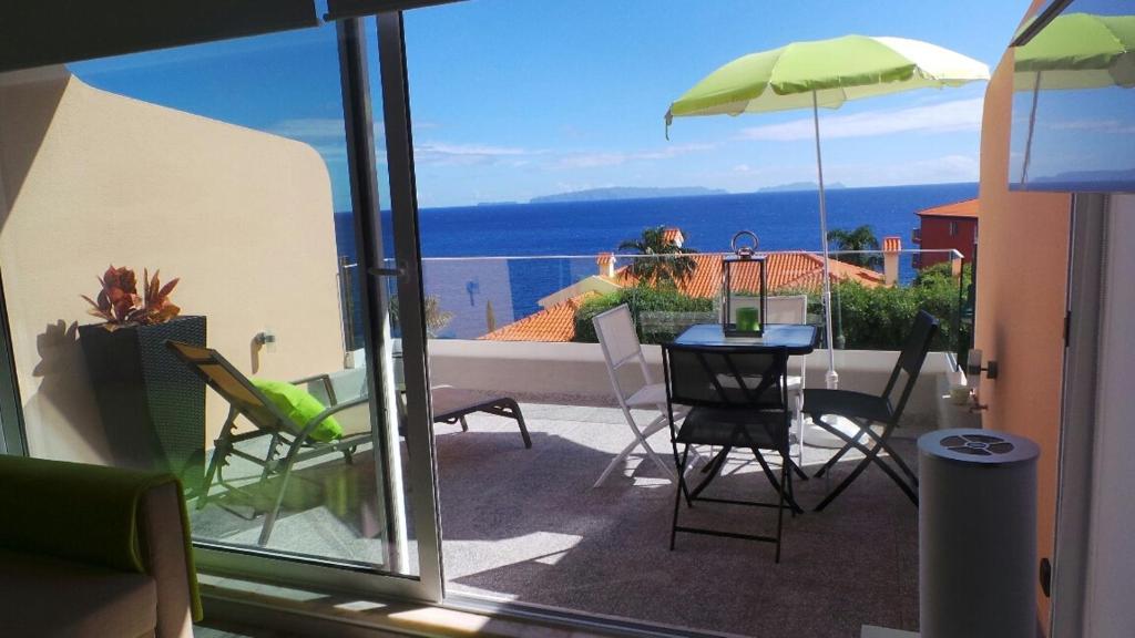 einen Balkon mit einem Tisch, Stühlen und einem Sonnenschirm in der Unterkunft Ventur Balcony in Caniço