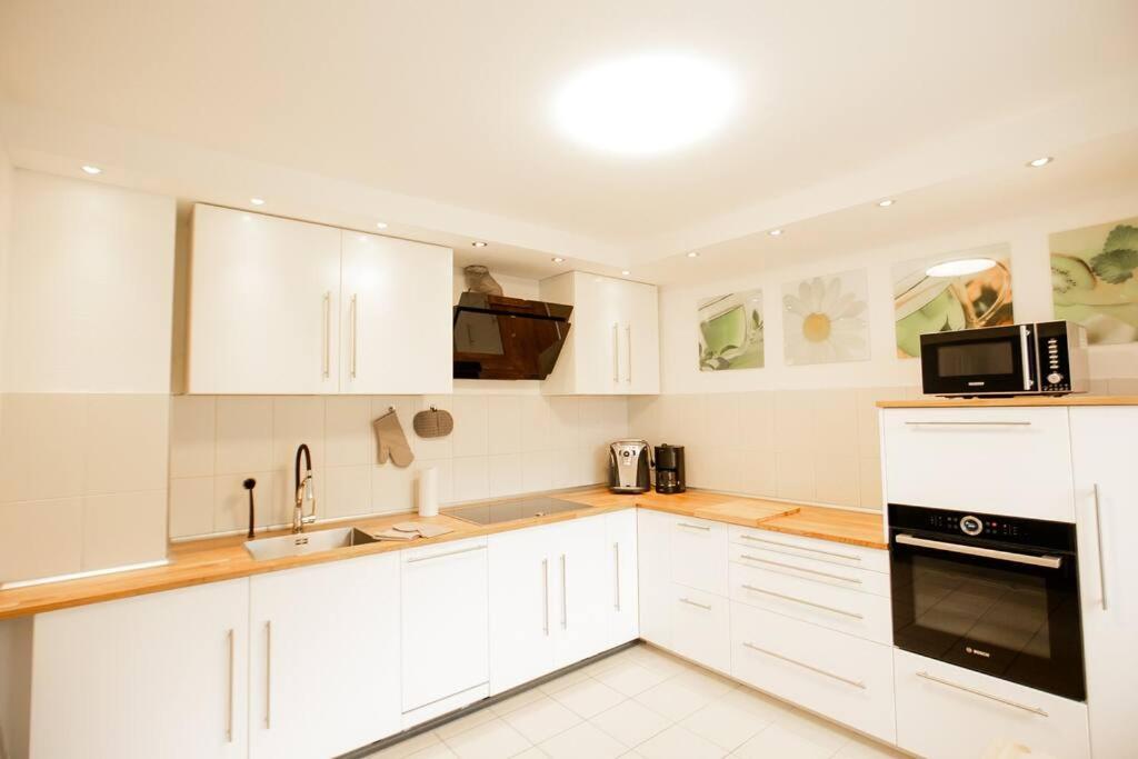 a white kitchen with white cabinets and a microwave at bonquartier - HOUSE - GARDEN - FOREST - TOP ROAD CONNECTION in Siegburg