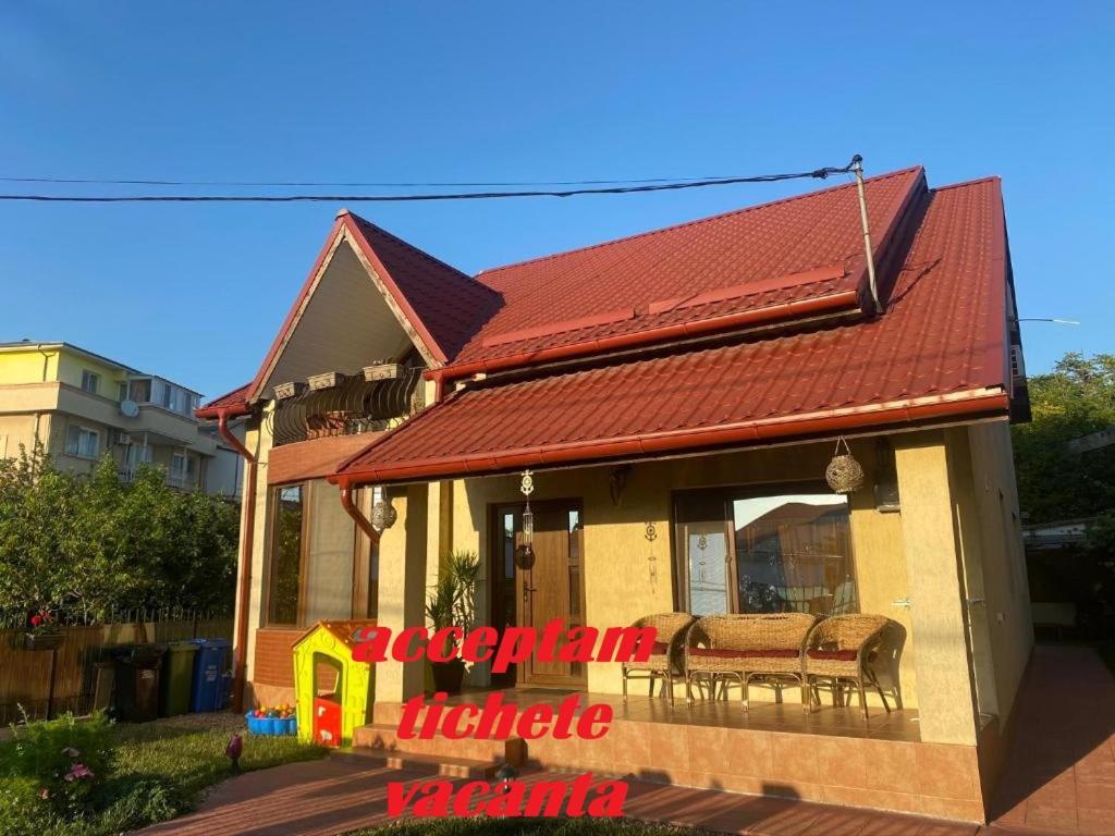 a house with a red roof and two chairs at Vila Lidia in Eforie Nord