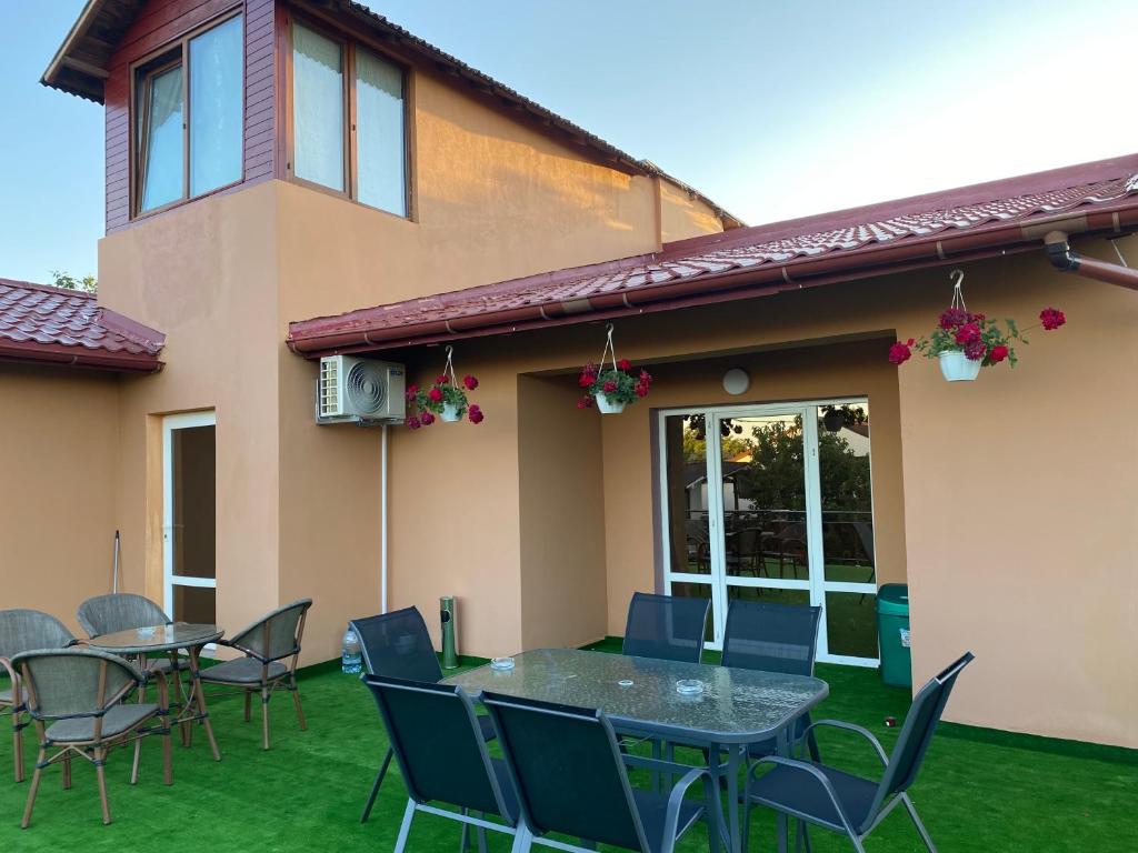 a patio with tables and chairs on a lawn at Vila Pișcoțel in Schitul