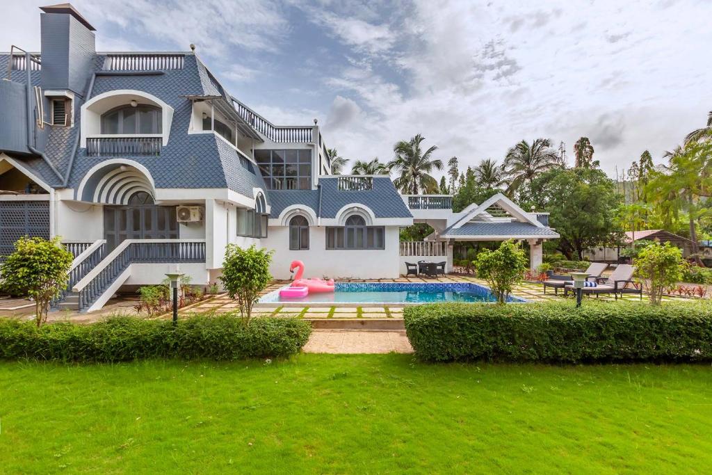 a large house with a swimming pool in front of it at Grey Mosaics by StayVista - Mountain-view villa in Vasai with Pool, Spacious lawn & Terrace in Mumbai