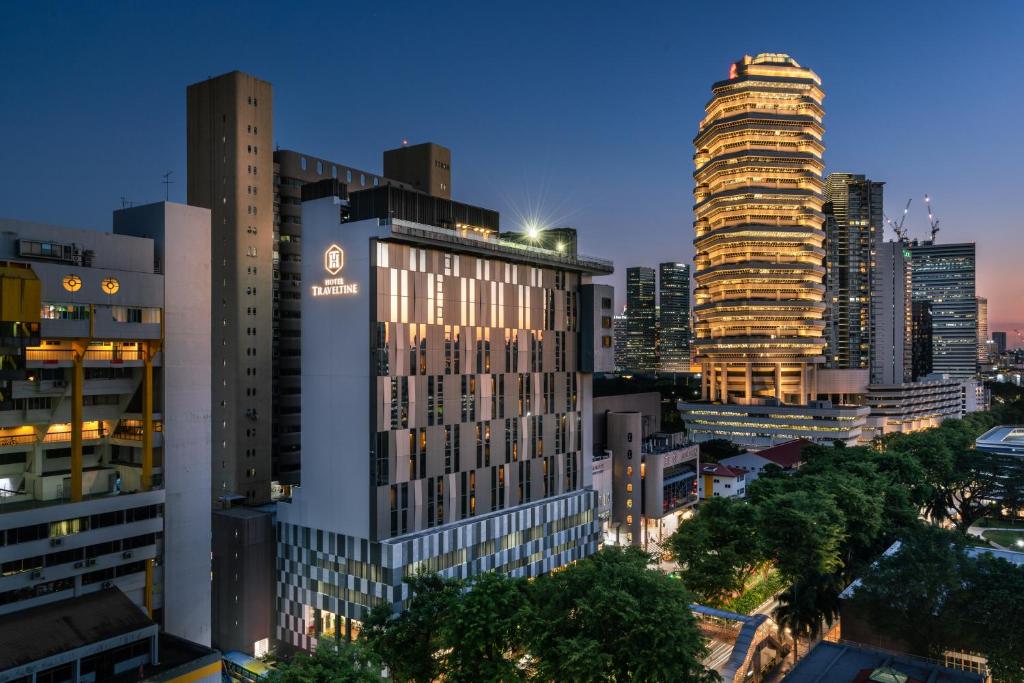 um horizonte da cidade à noite com edifícios altos em Hotel Traveltine em Singapura