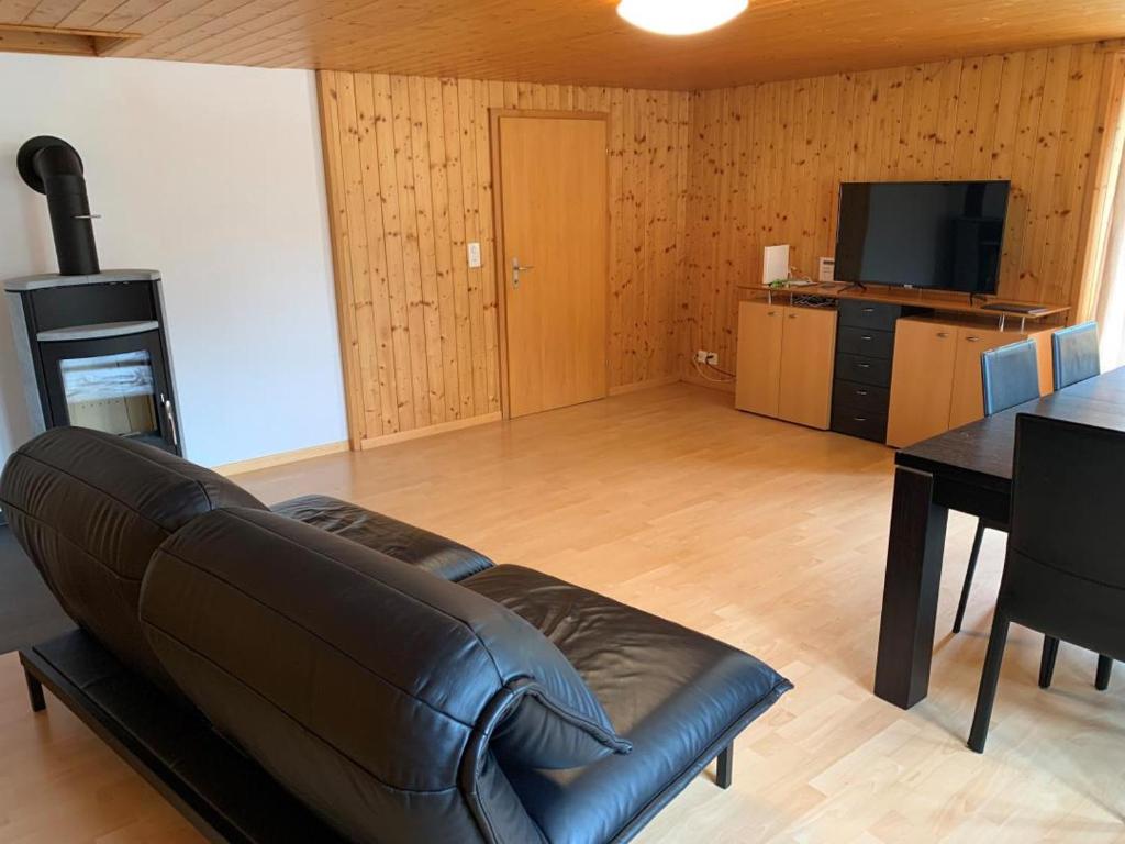 a living room with a black leather couch and a table at Revier Bliili und Spitzer in Diesbach