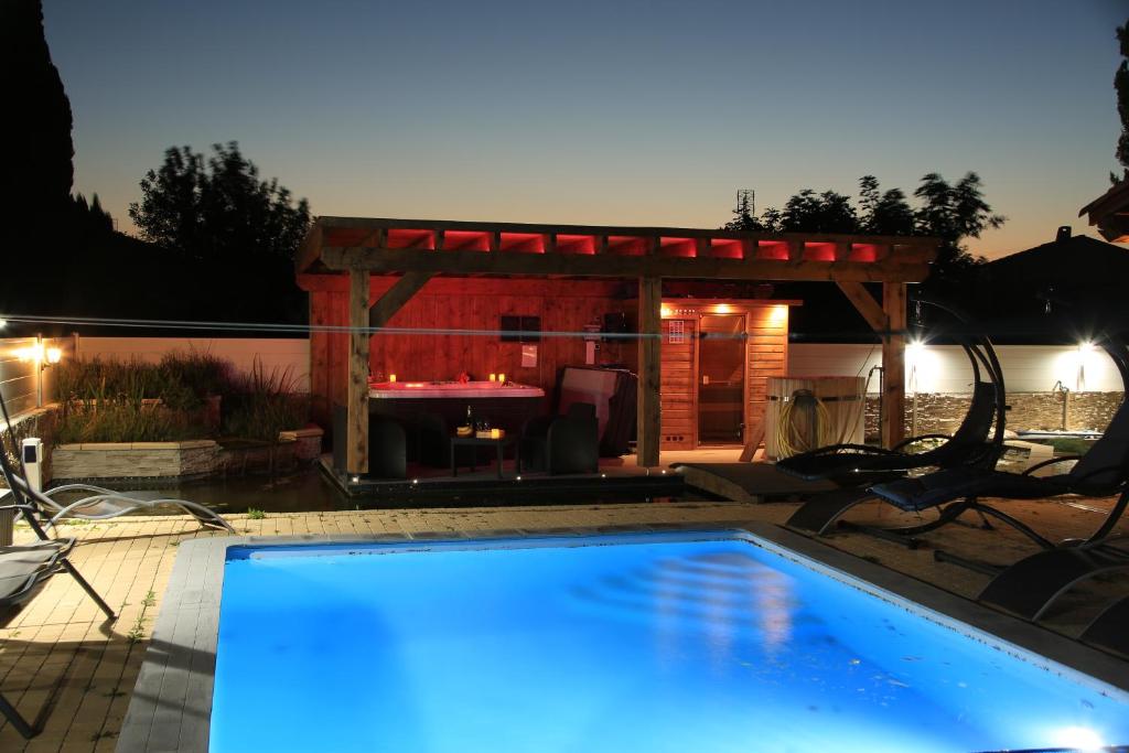 a swimming pool with a fireplace in a backyard at night at Chalet Mont Ventoux et Chalet VIP in Camaret-sur-Aigues