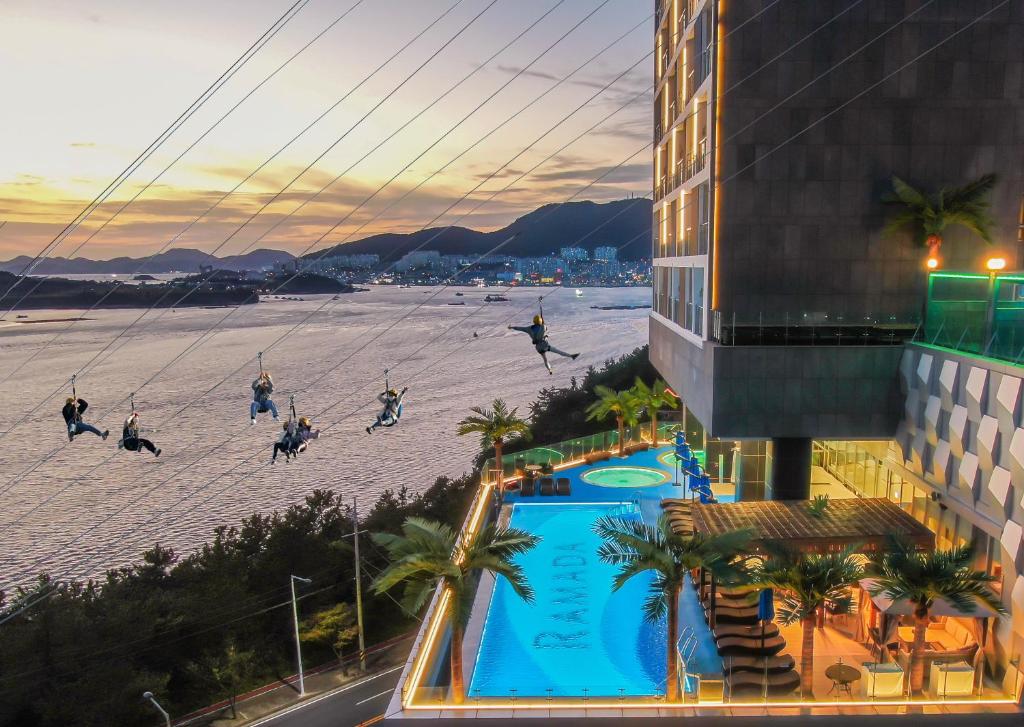 麗水的住宿－Ramada Plaza by Wyndham Dolsan Yeosu，一群人在海滩上,设有一个游泳池