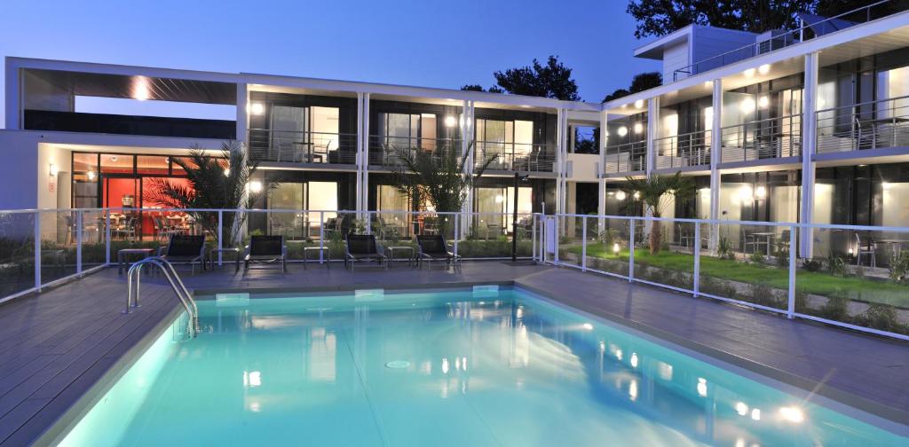 a swimming pool in front of a building at Hotel Eden Park Pau Est, avec Piscine in Pau