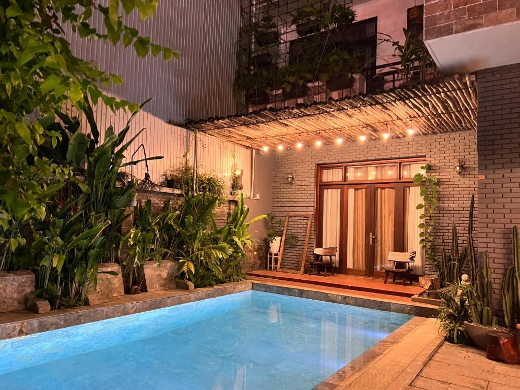 a swimming pool with plants in front of a building at Chaca Beach House in Da Nang