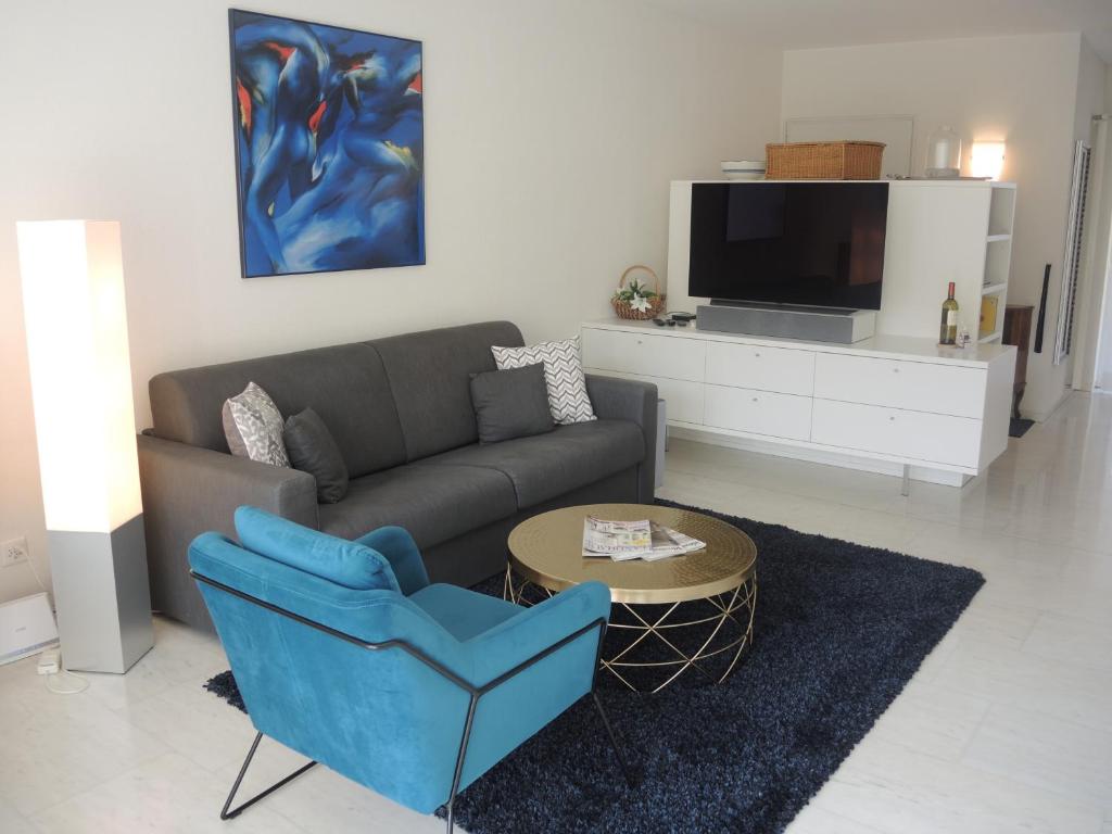 ein Wohnzimmer mit einem Sofa, einem Tisch und einem TV in der Unterkunft Alice Holiday Apartment in Locarno