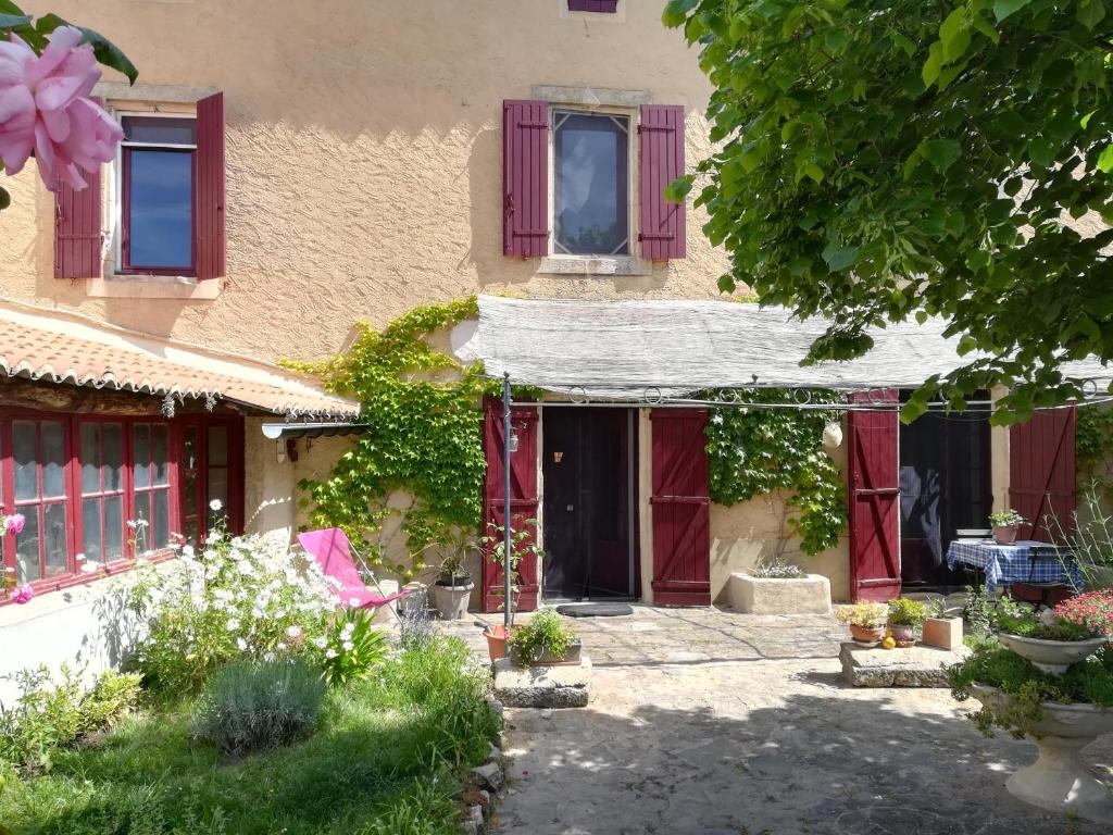 una casa con puertas rojas y flores en el patio en Mas d'Antan, en Saint-Paul-les-Fonts