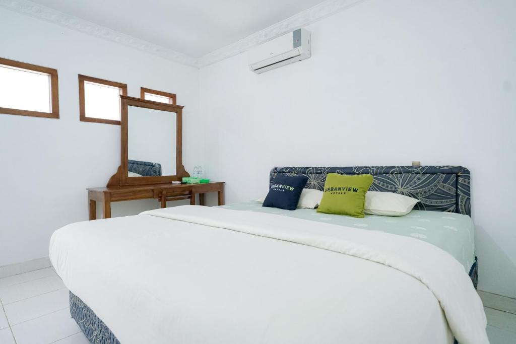 a white bed in a room with a mirror at Urbanview Hotel Syariah Ratu Kuring Gisting by RedDoorz in Banjarnegeri