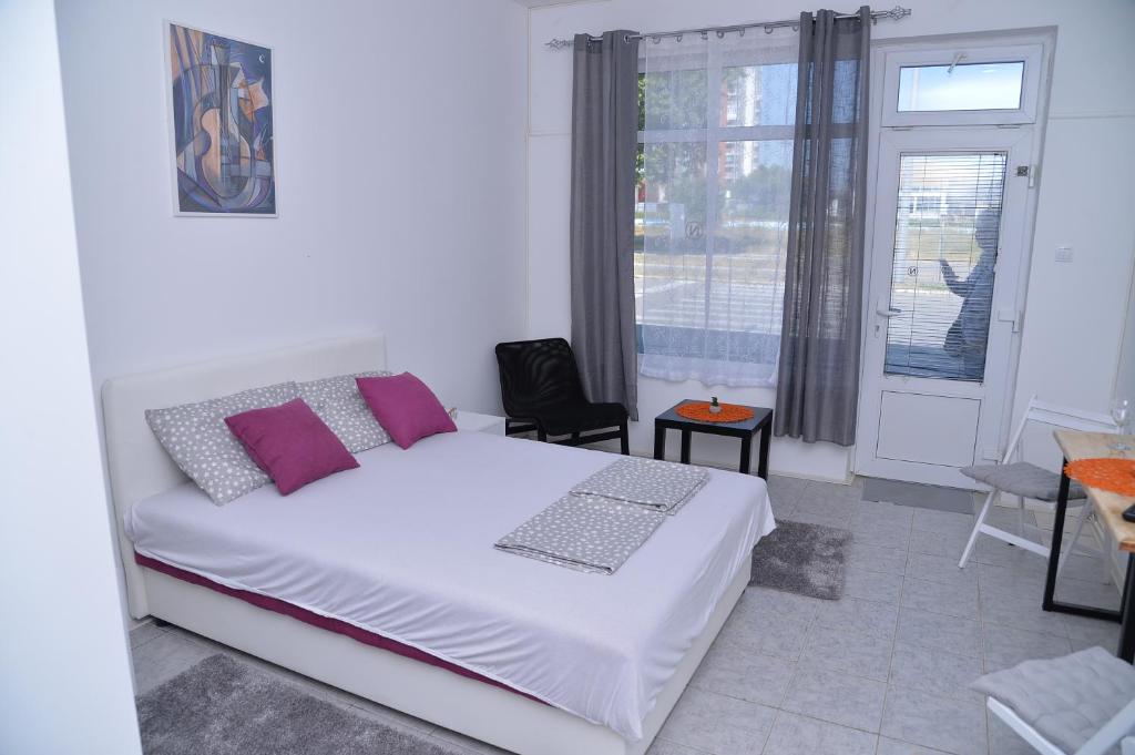 sypialnia z dużym białym łóżkiem i oknem w obiekcie Apartments INN Smederevska Palanka w mieście Smederevska Palanka