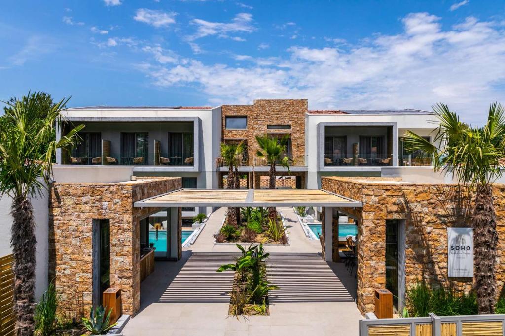 an exterior view of a resort with palm trees at Soho Exclusive Suites in Skala Potamias