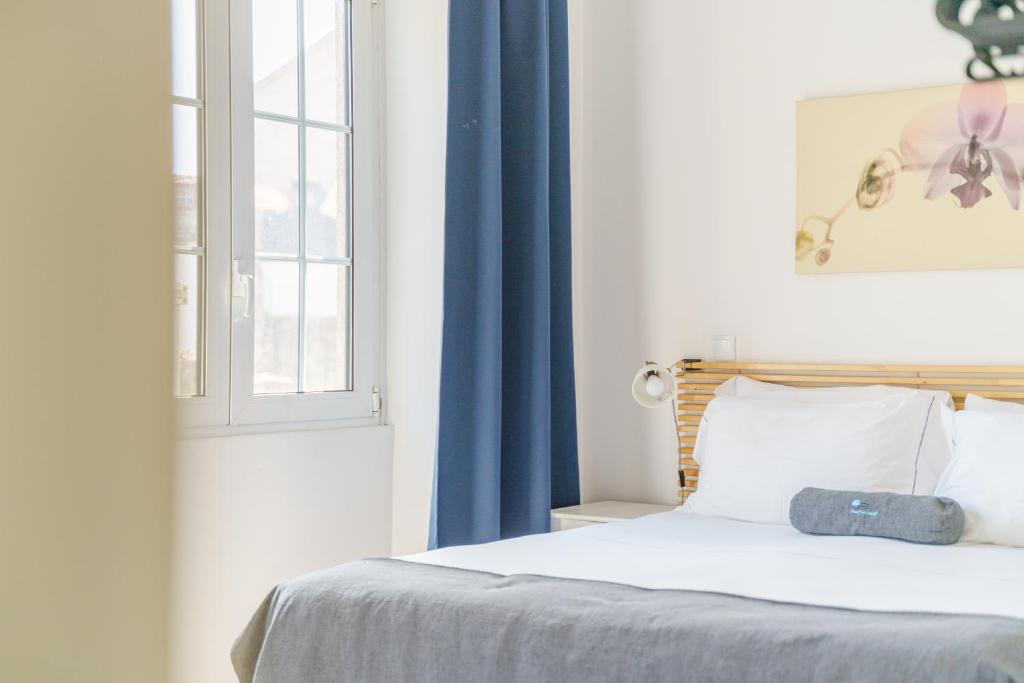 1 dormitorio con 1 cama con cortina azul y ventana en Feel Porto Historical Apartments, en Oporto