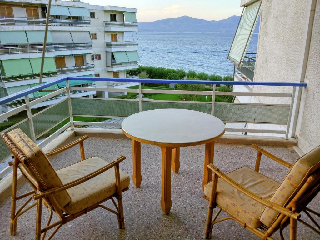 einen Tisch und zwei Stühle auf einem Balkon mit Meerblick in der Unterkunft Διαμέρισμα δίπλα στη θάλασσα, παραλία Μαρκοπούλου in Oropos