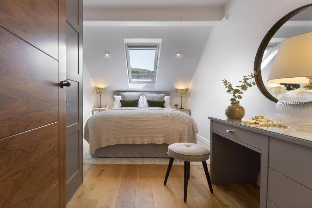 a bedroom with a bed with a mirror and a stool at Rohan Rise - Lake District Escape for Two in Ambleside
