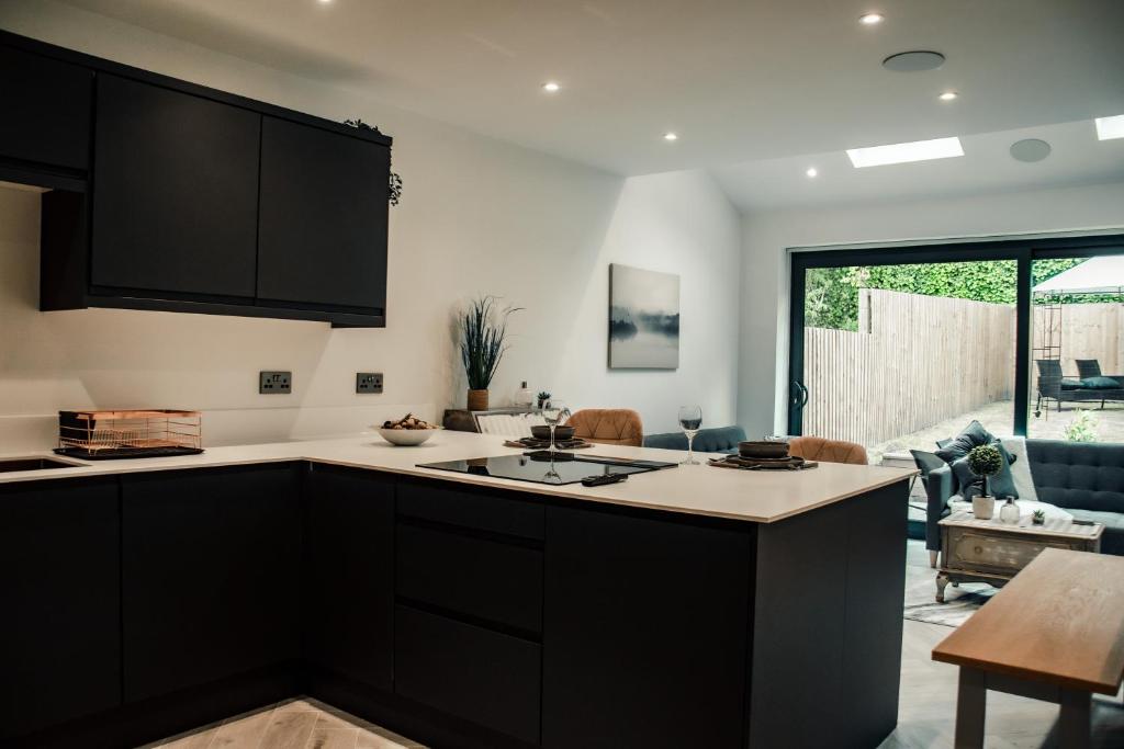 a kitchen with black cabinets and a living room at Bv Luxury 3 Bedroom Townhouse At Bed Cliff Oaks in Leeds