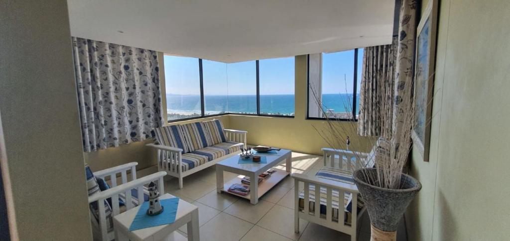 a living room with a couch and tables and windows at Accommodation Front - Tastefully Furnished 6 Sleeper with Ocean Views in Durban