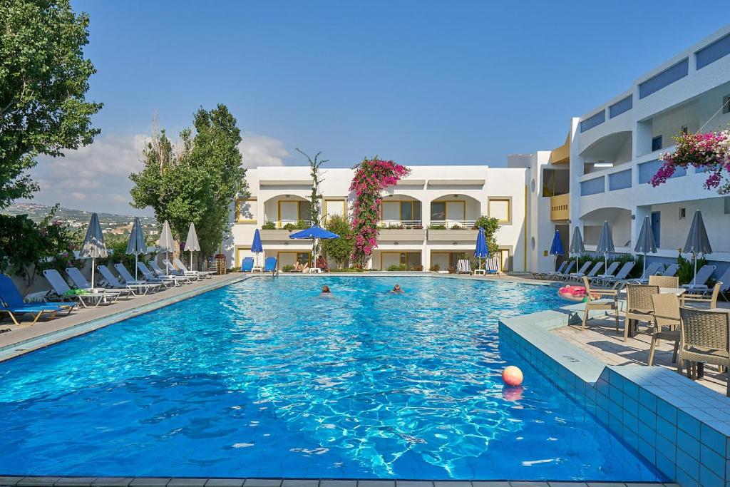 a large swimming pool with chairs and a hotel at Apollon Hotel Apartments in Platanes