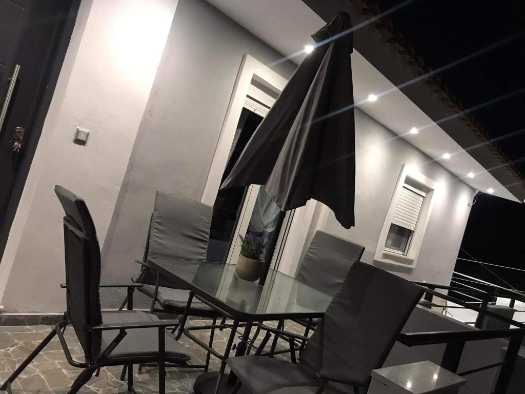 una mesa de cristal con sillas y una sombrilla en John’s shared apartment, en Artemida