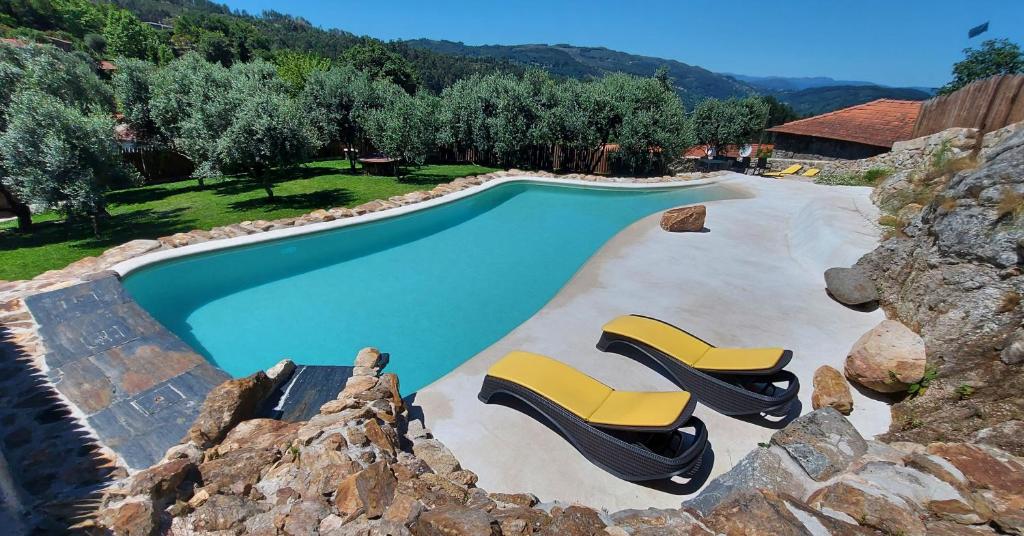 a swimming pool with two yellow lounge chairs next to it at Casa Guardião do Castelo in Celorico de Basto