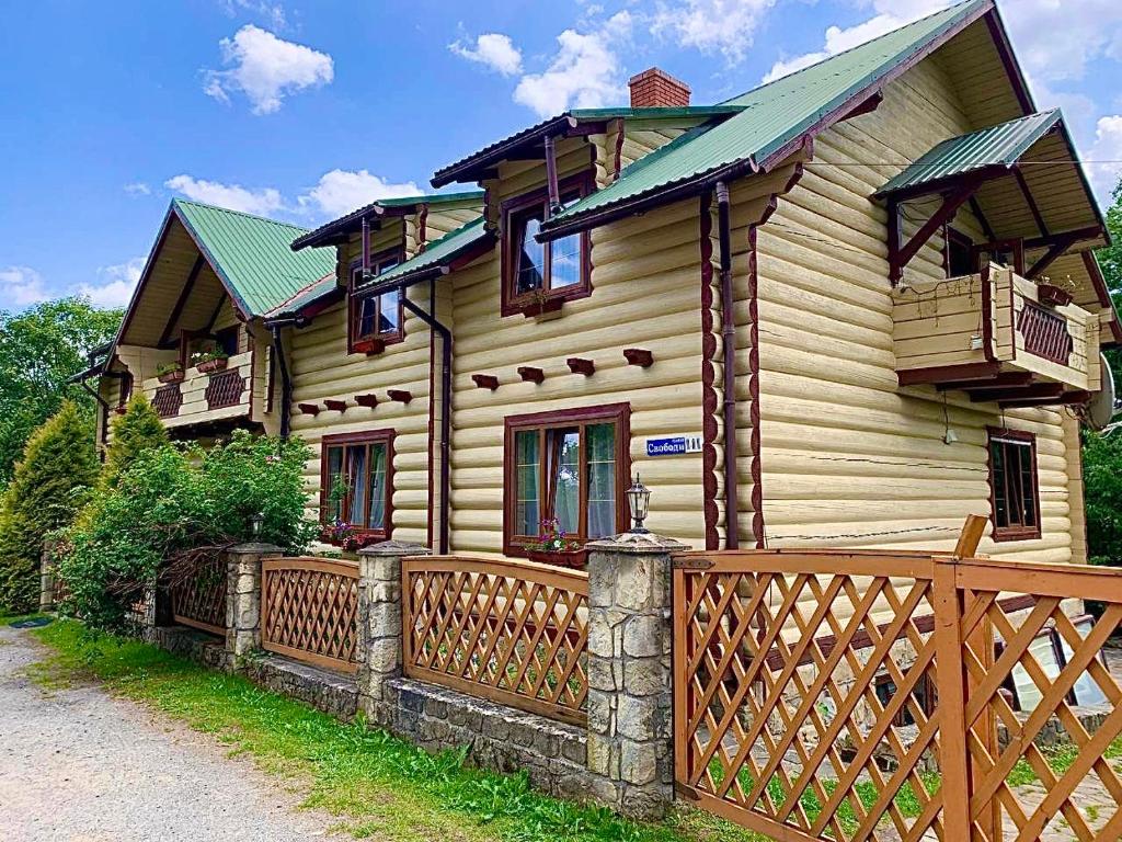 una casa in legno con una recinzione di fronte ad essa di Family a Jaremče