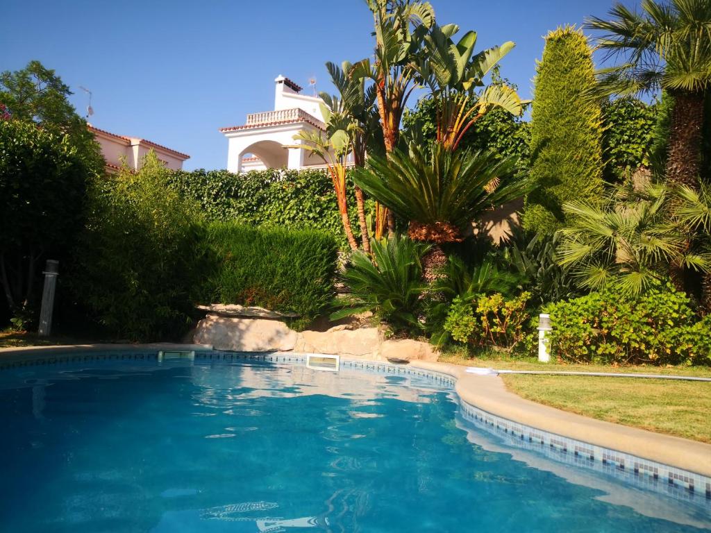 a swimming pool in front of a house with palm trees at Villa Tito in Cunit