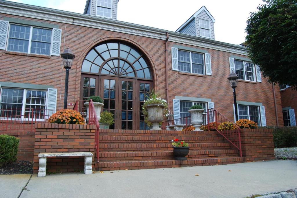 a brick building with stairs and flowers in front of it at Colts Neck Inn Hotel in Colts Neck