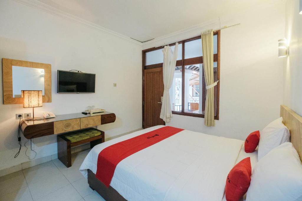 a bedroom with a bed and a desk and a television at RedDoorz at Bali Kepundung Denpasar in Denpasar