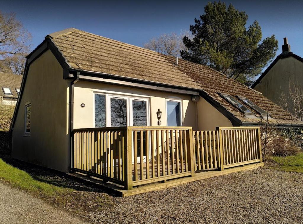 a small house with a wooden fence in front of it at Awdry Bungalow in Beaworthy