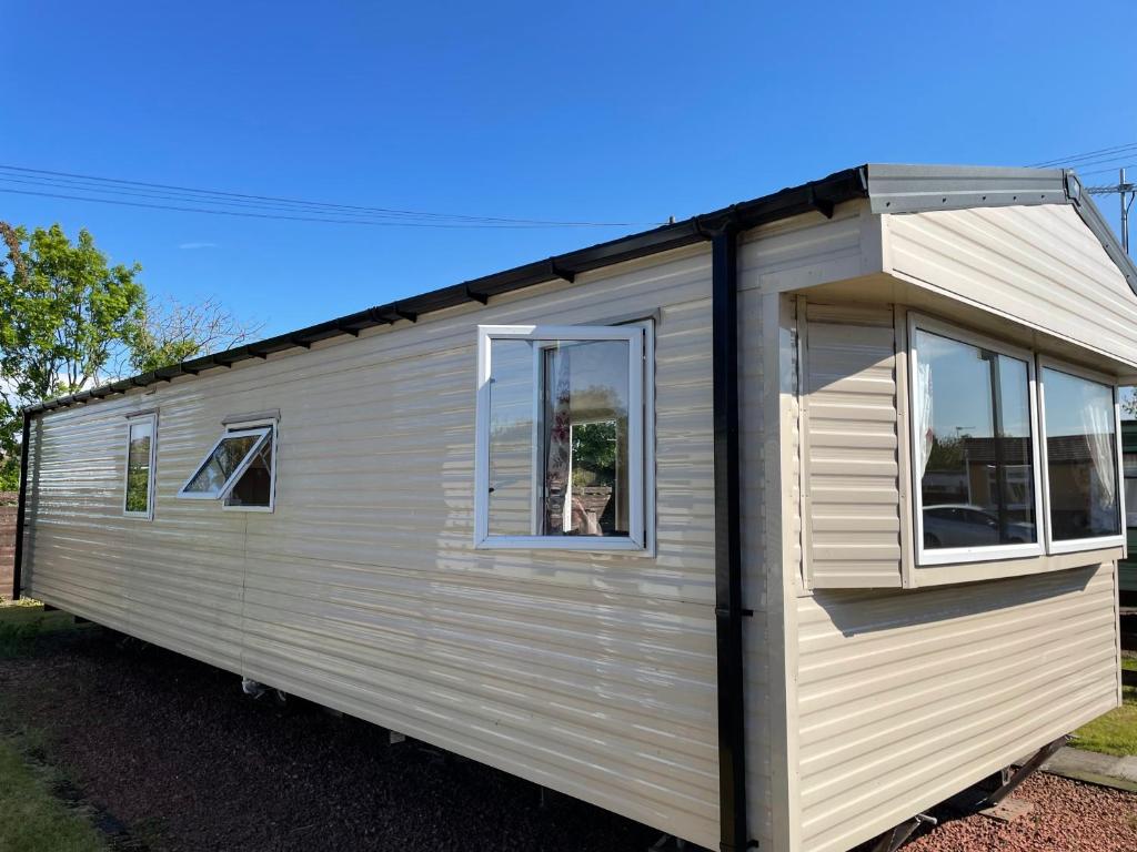 Two Bedroom Willerby Parkhome in Uddingston, Glasgow في أودينغستن: مقطورة بيضاء صغيرة مع نوافذ على شارع