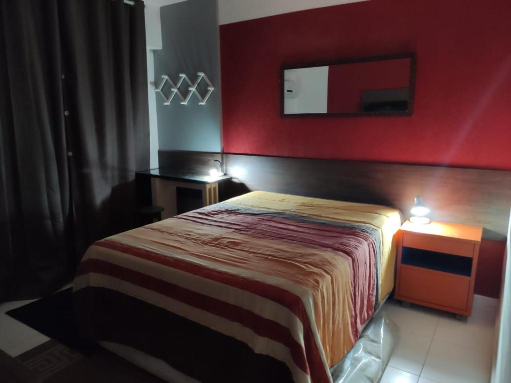 Habitación de hotel con cama y pared roja en Suite Rio stay, en Río de Janeiro