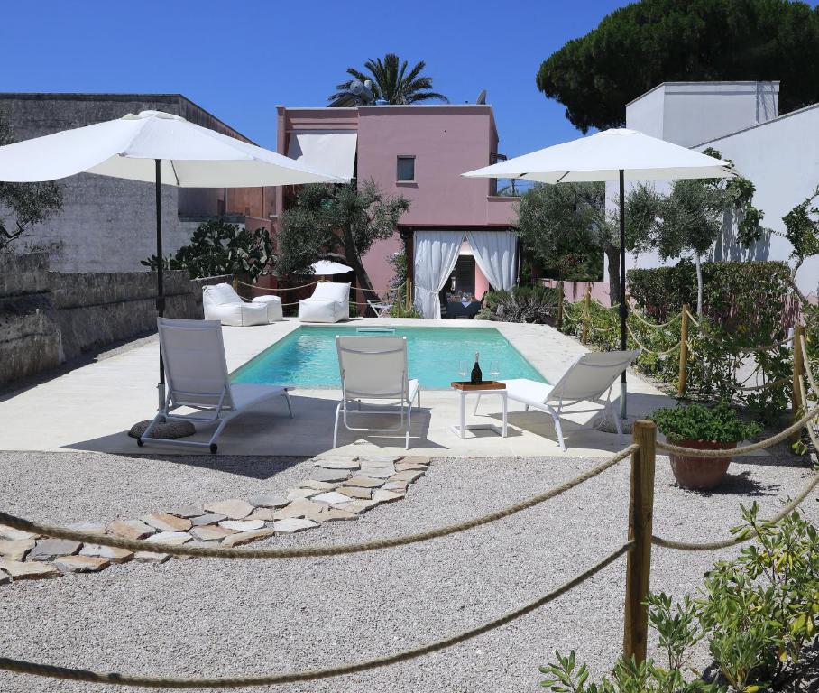 a swimming pool with two chairs and umbrellas at B&B Happy Days Golfo di Gallipoli in Santa Maria al Bagno