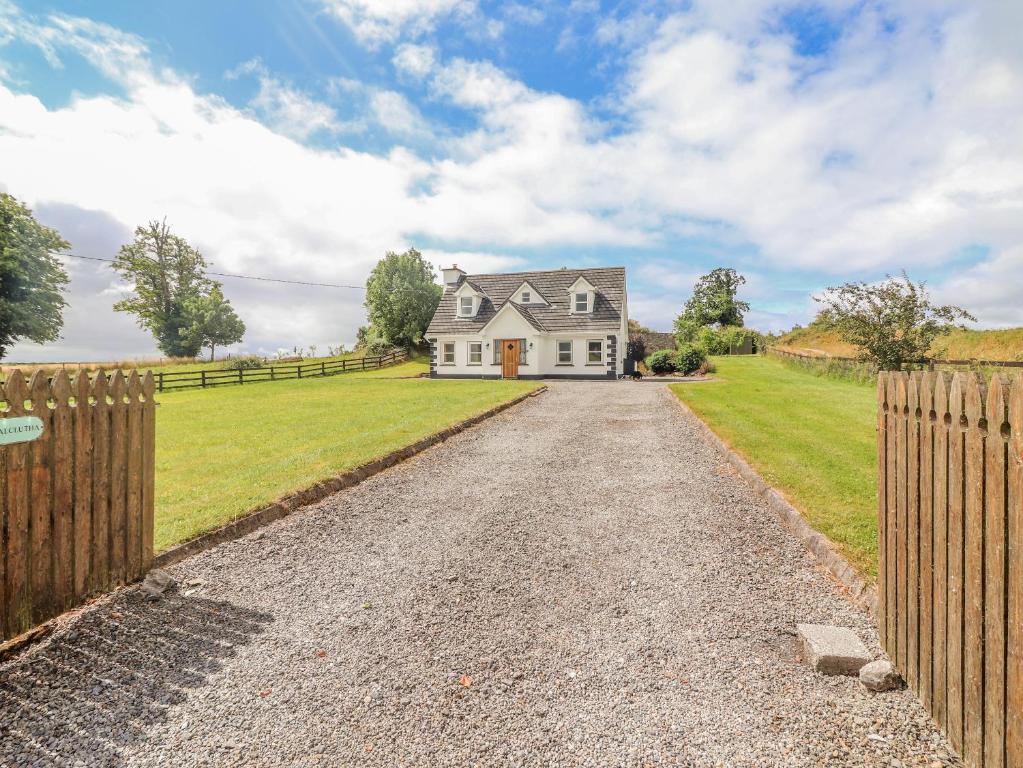 una entrada que conduce a una casa blanca con una valla en Meadow View en Nenagh