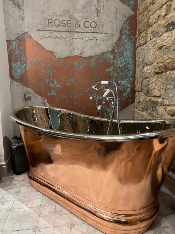 a copper tub in a bathroom with a stone wall at Mulberry House - Morpeth Town Centre - Hot Tub in Morpeth