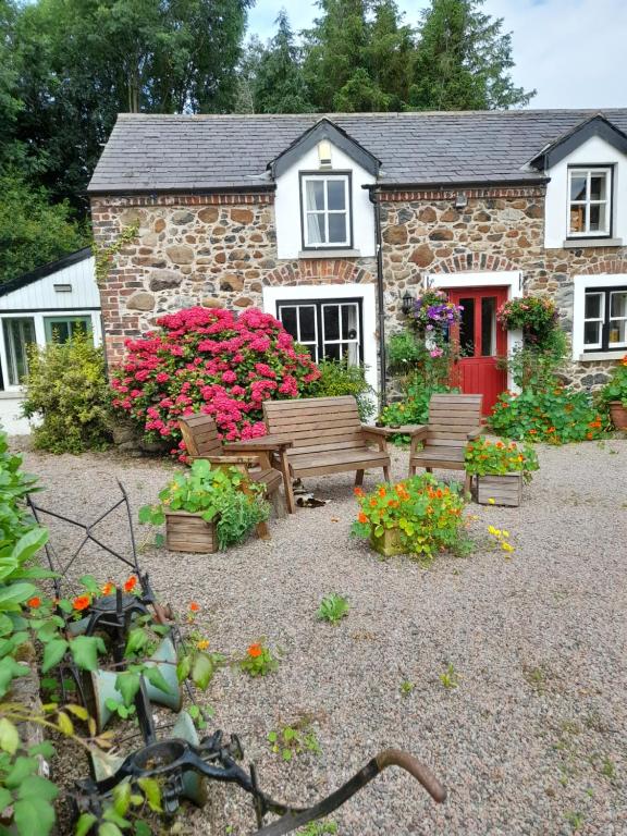 a house with benches and flowers in front of it at Berwick Hall Cottage in Moira