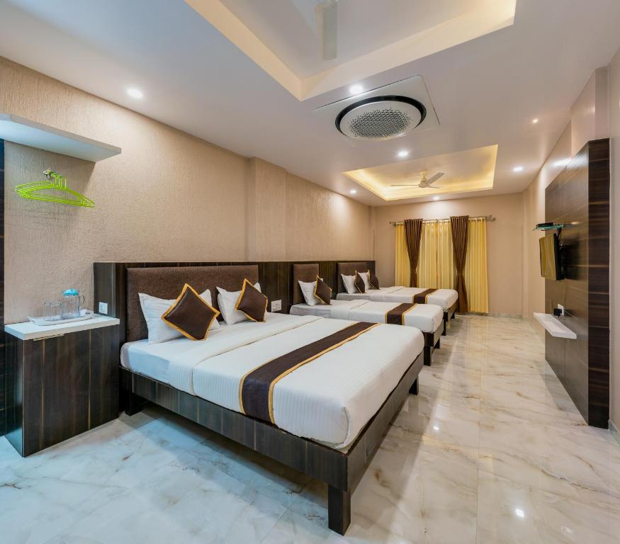a row of beds in a hotel room at Hotel Aatithya Satkar Near Mahalaxmi Temple in Kolhapur