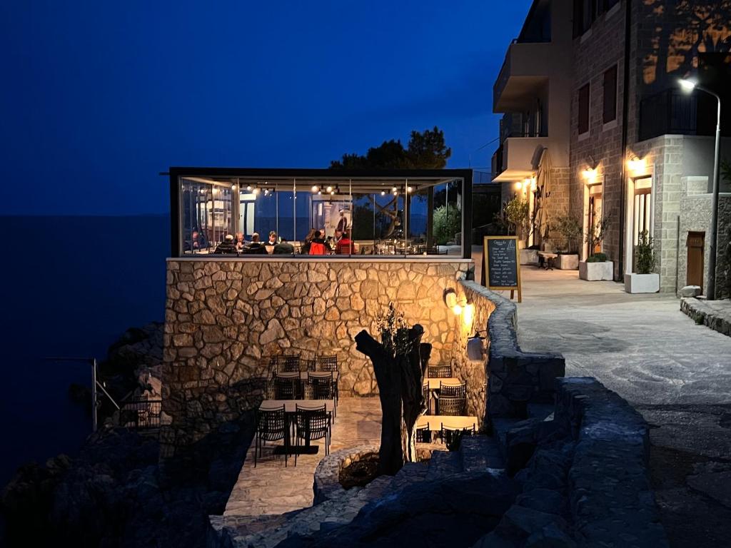 a building with a stone wall with a bar at Apartments Capocesto in Primošten