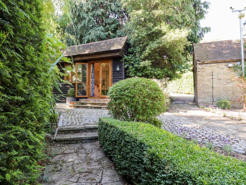 ein kleines Haus in einem Garten mit Büschen in der Unterkunft Willow Cottage in Dartford