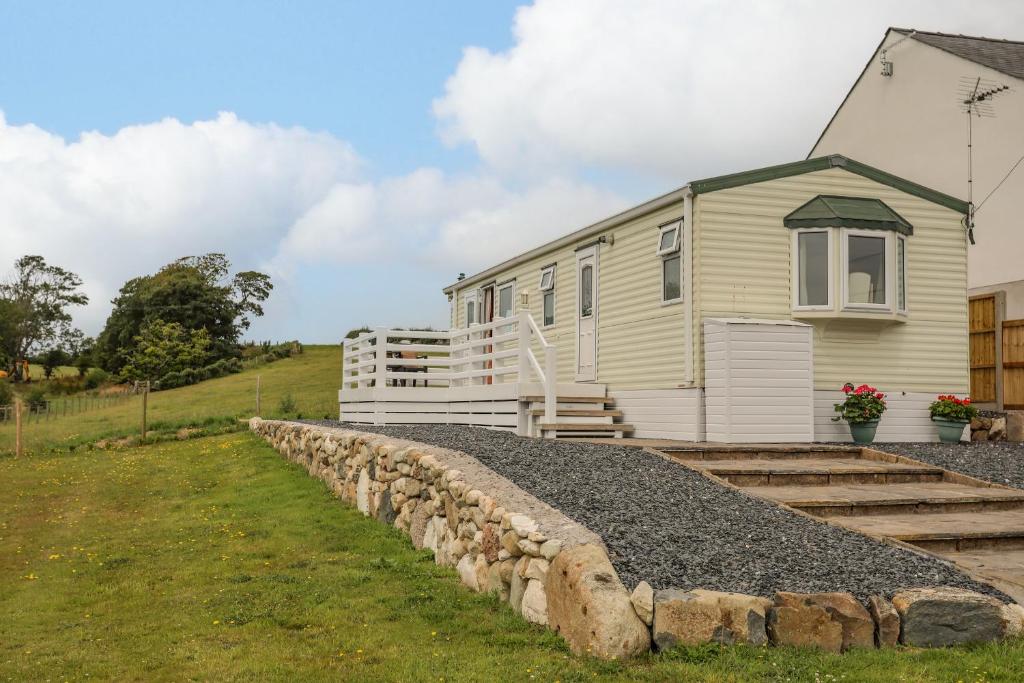 a house with a stone wall in front of it at Ty Newydd Caravan in Pwllheli