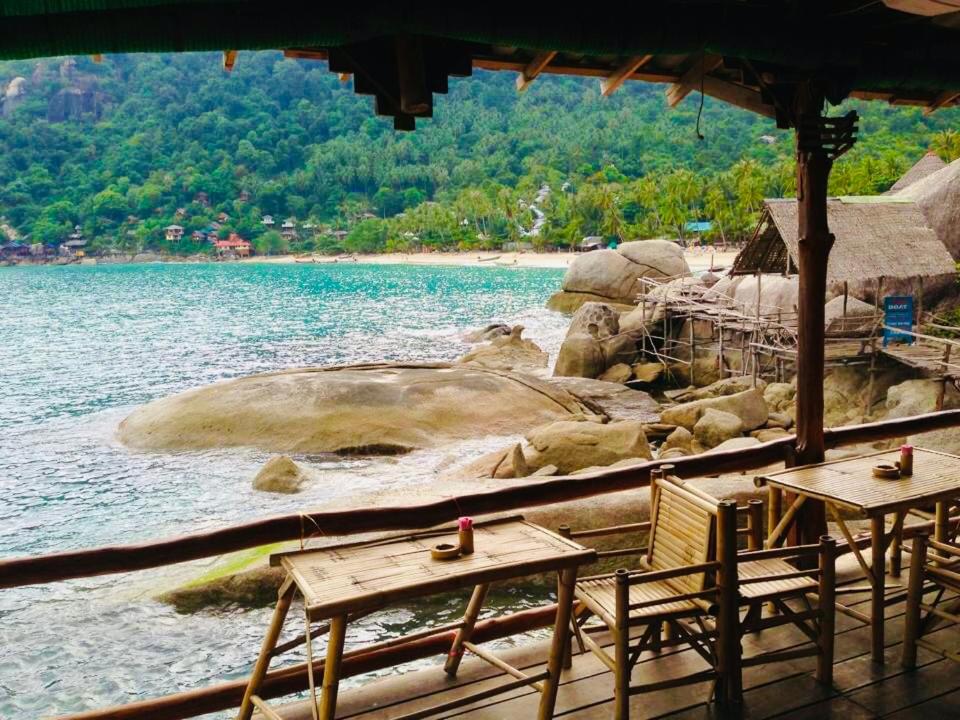 a beach with two tables and chairs and the water at Bambu Huts in Baan Tai