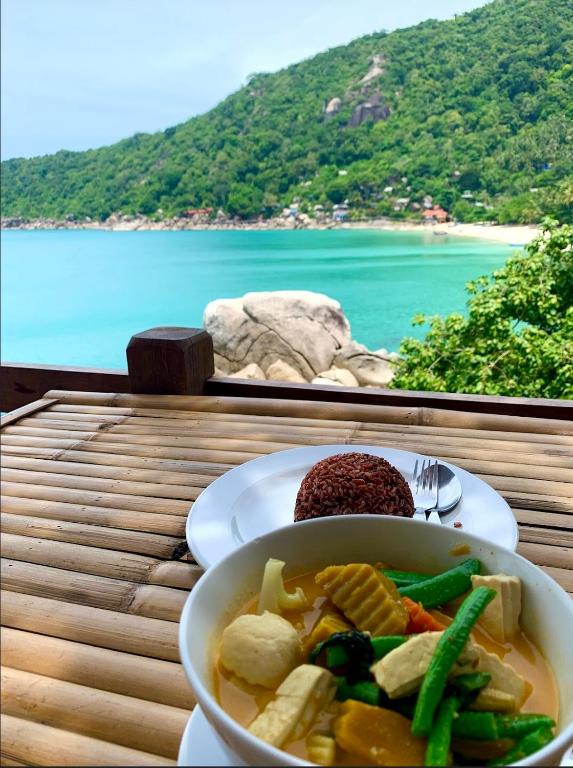 a bowl of soup on a table with a view of the ocean at Bambu Huts in Baan Tai