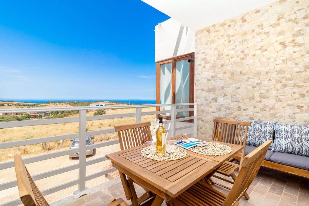 drewniany stół i krzesła na balkonie z plażą w obiekcie Sardegna Appartamenti, Via Sedini w mieście Trinità dʼAgultu