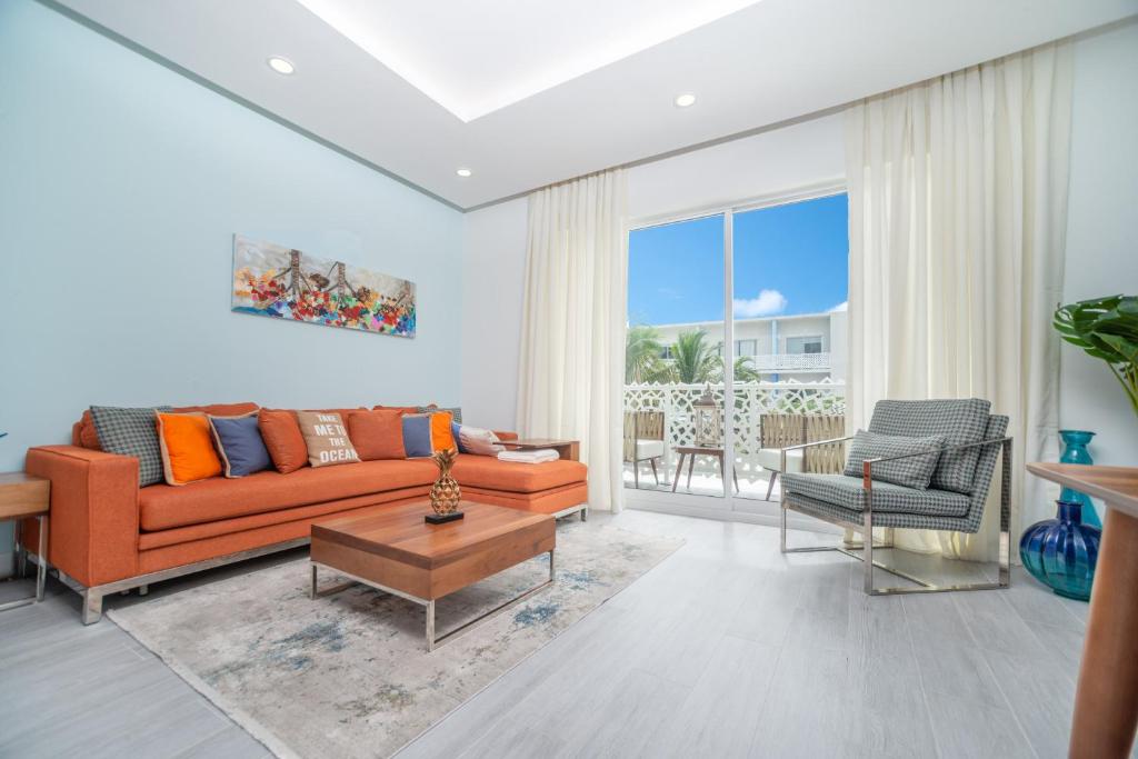a living room with an orange couch and a table at Luxury 1 bed apartment near Seven Mile Beach at The Grove - Villa Island Life in Upper Land